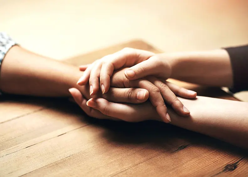 Hands holding each other on table